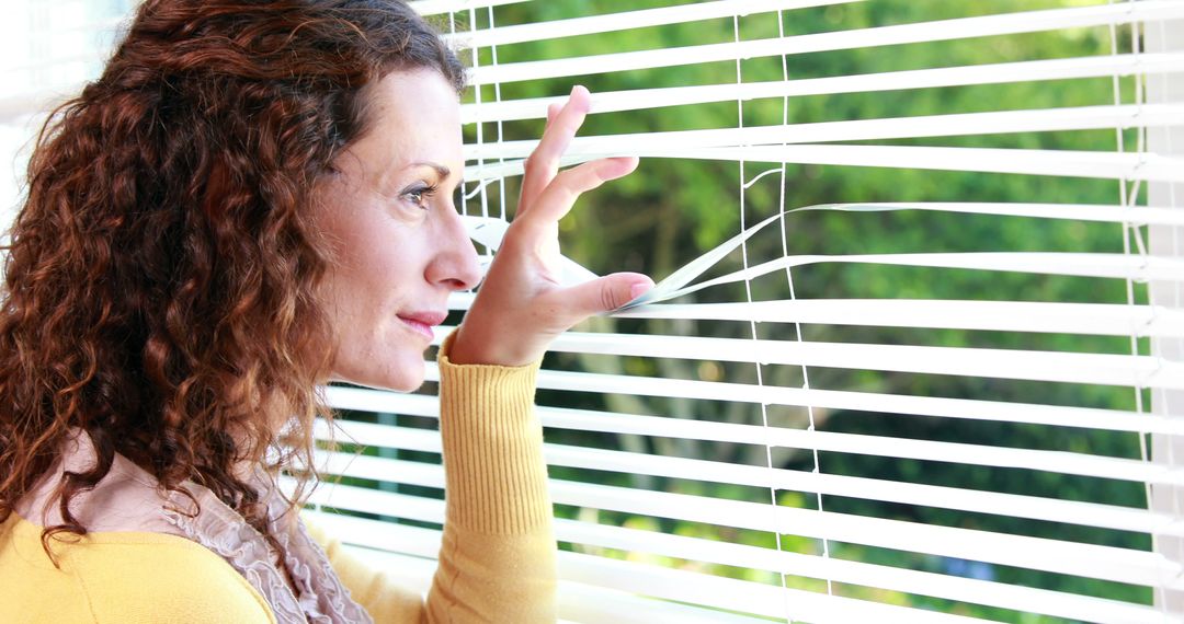 Woman Looking through Window Blinds Feeling Curious - Free Images, Stock Photos and Pictures on Pikwizard.com