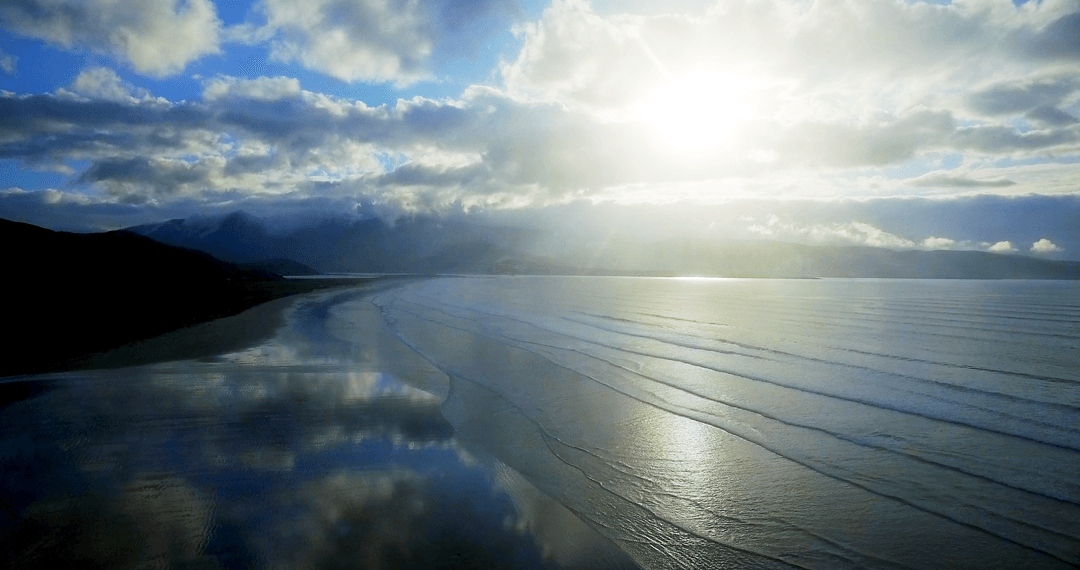 Transparent Sea reflecting Cloud Shadows on Sunny Day at Tranquil Beach