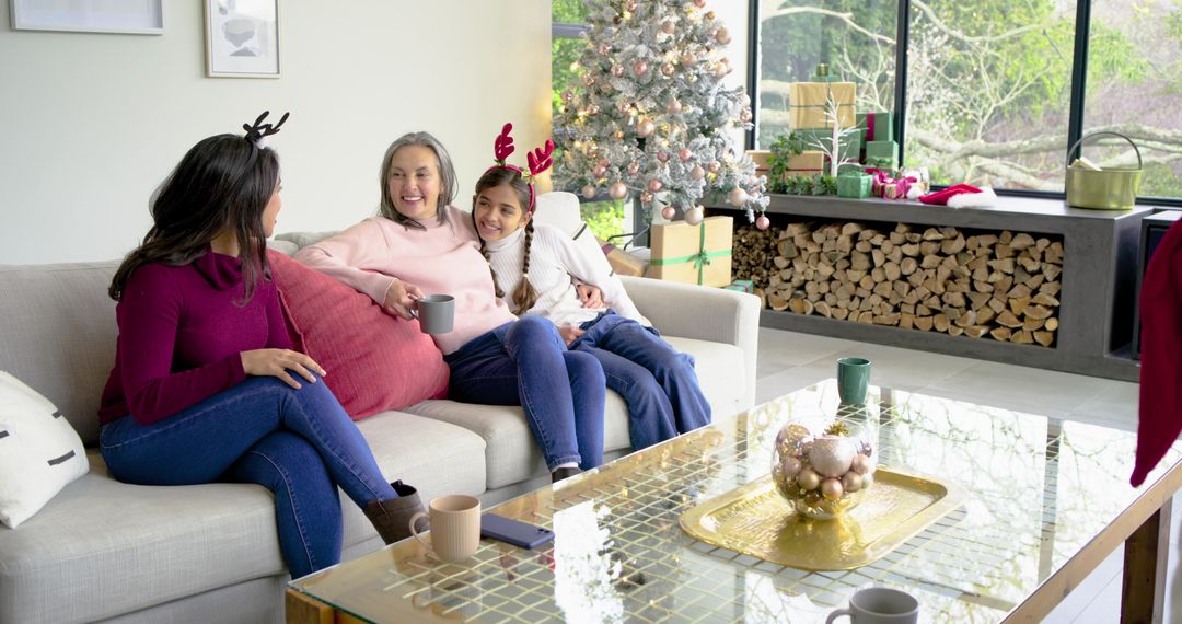 Multigenerational family relaxing on sofa with mugs by decorated Christmas tree and gifts