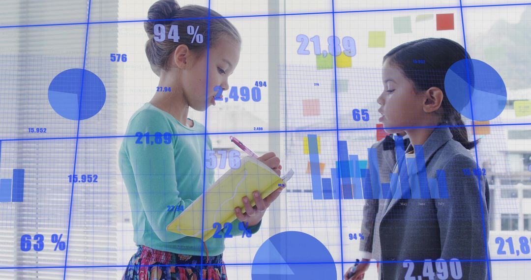 Two girls collaborating on data writing notes on yellow notebook with blue charts overlay