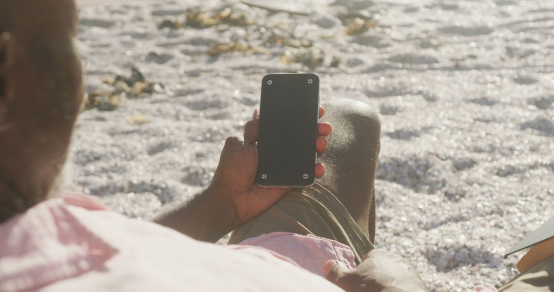 Man Relaxing on Beach Holding Smartphone with Blank Screen - Free Images, Stock Photos and Pictures on Pikwizard.com