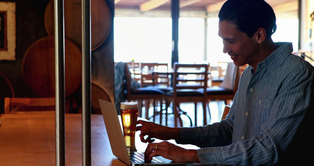 Asiatic Young Man at Bar Working Remotely on Laptop