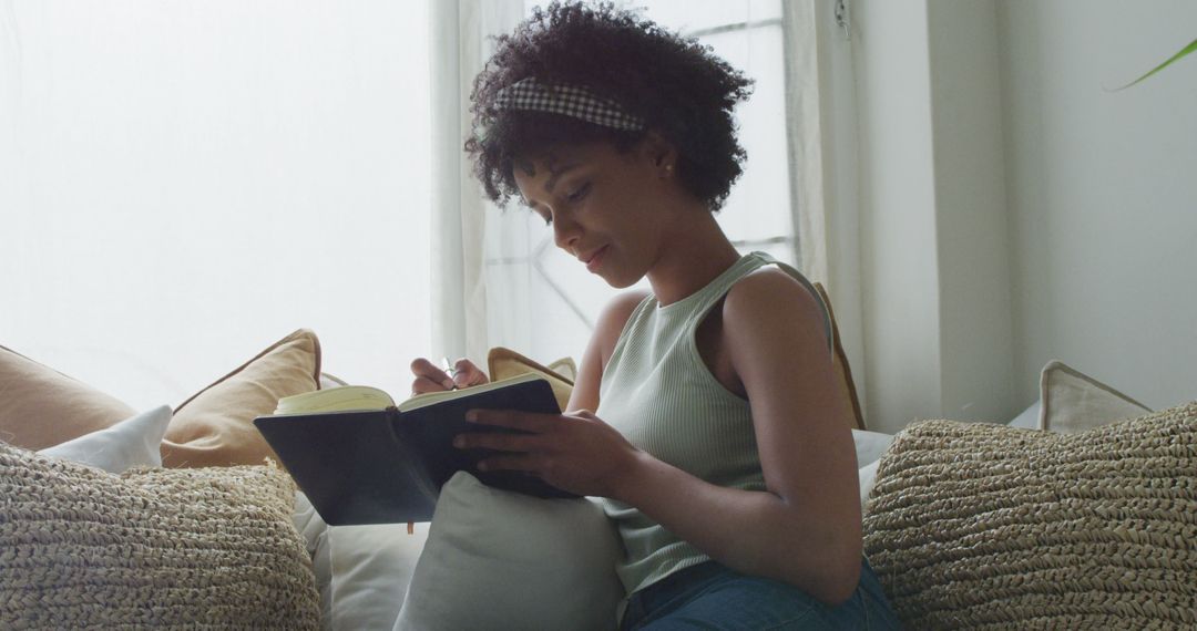 Image of happy biracial woman relaxing at home, writing in notebook, with copy space - Free Images, Stock Photos and Pictures on Pikwizard.com