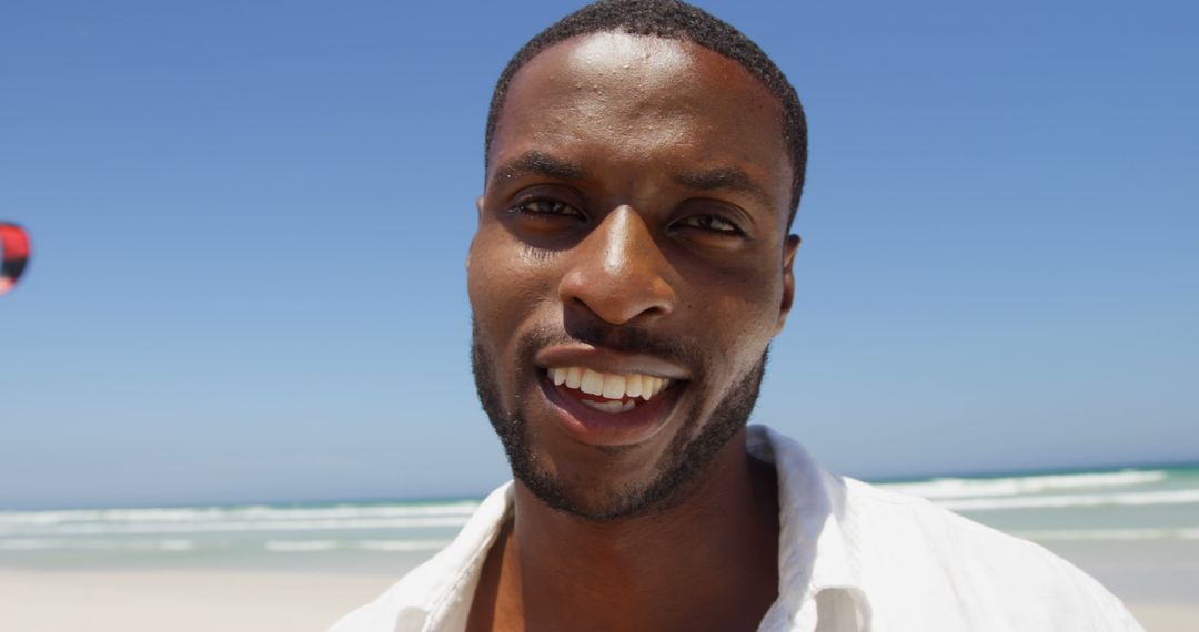 A cheerful African American man enjoys a sunny day at the beach, with copy space - Free Images, Stock Photos and Pictures on Pikwizard.com