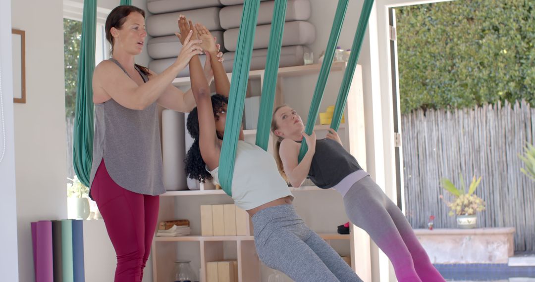 Women Practicing Aerial Yoga with Instructor in Well-Lit Studio - Free Images, Stock Photos and Pictures on Pikwizard.com