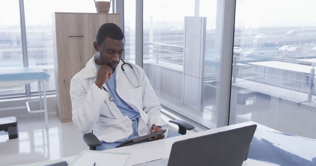 Focused African American Doctor Using Tablet in Modern Clinic - Free Images, Stock Photos and Pictures on Pikwizard.com