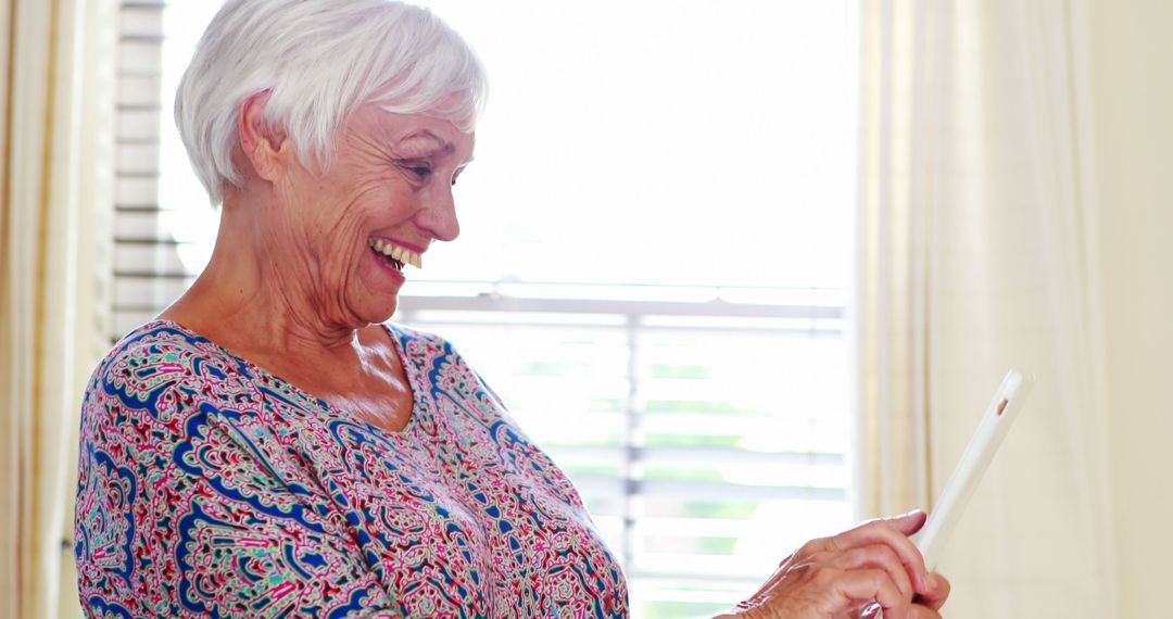 Senior Woman Smiling While Using Tablet at Home - Free Images, Stock Photos and Pictures on Pikwizard.com