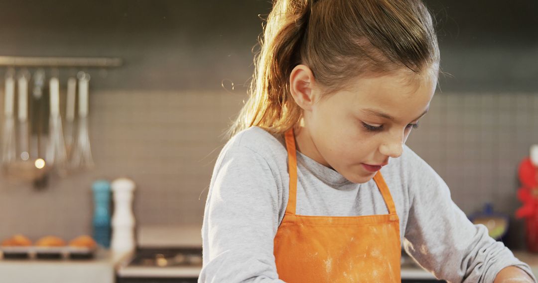 Young Girl Baking in Kitchen Wearing Orange Apron - Free Images, Stock Photos and Pictures on Pikwizard.com