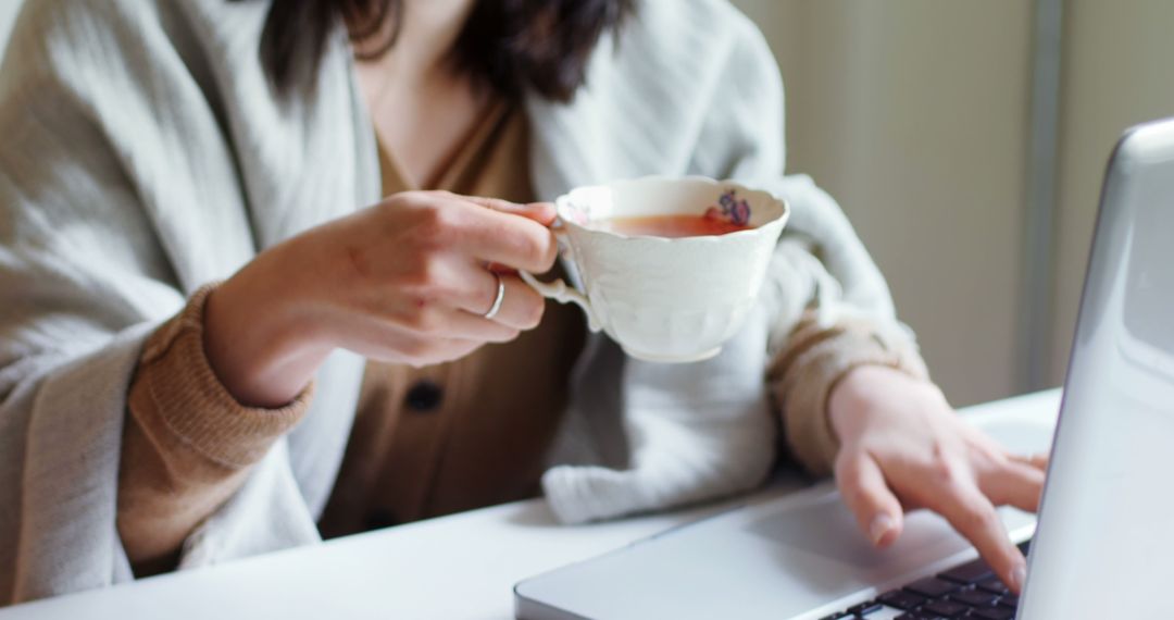 Woman Working on Laptop and Drinking Tea in Cozy Setting - Free Images, Stock Photos and Pictures on Pikwizard.com