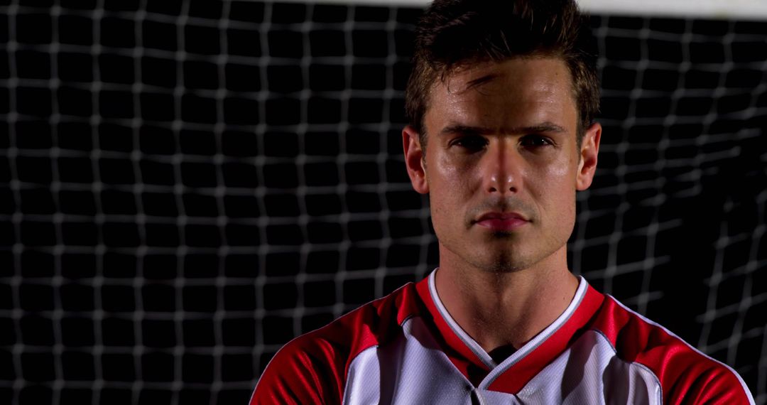 Confident Soccer Player Posing In Red White Jersey Against Goal Net