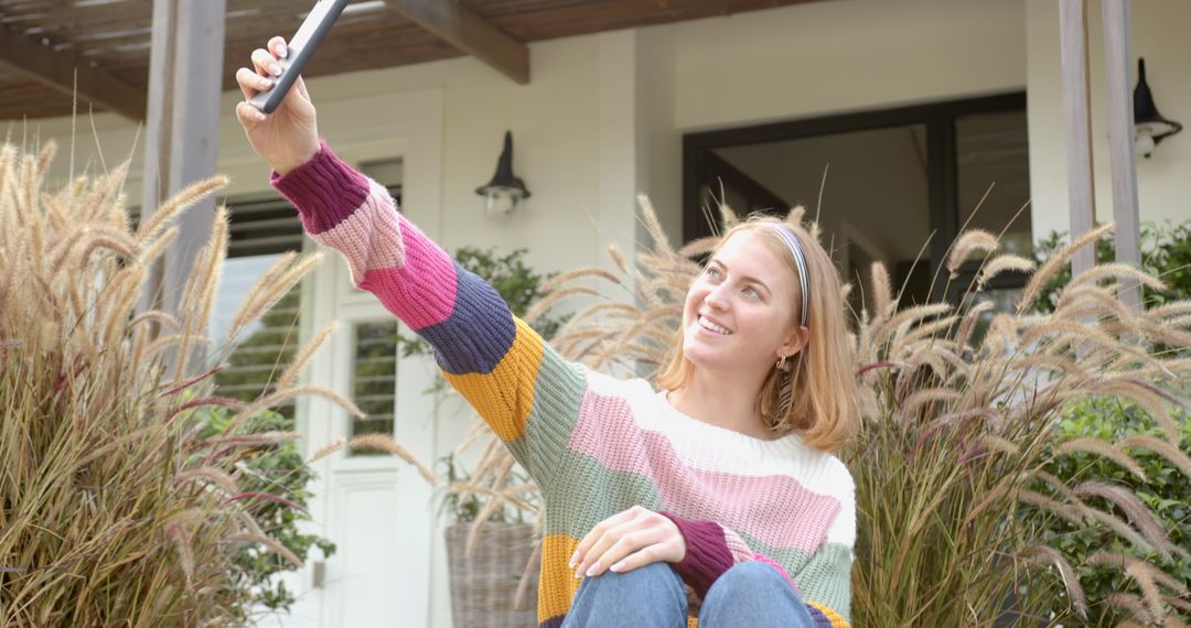 Woman Taking Selfie on Front Porch with Stylish Sweater and Nature Backdrop