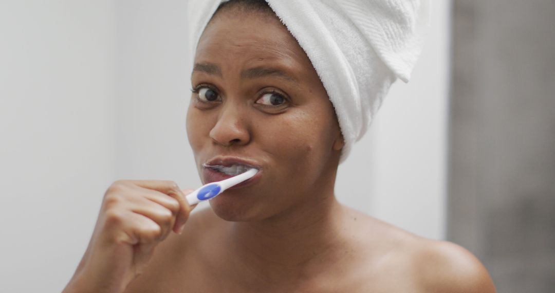 Happy african american woman brushing teeth in bathroom - Free Images, Stock Photos and Pictures on Pikwizard.com