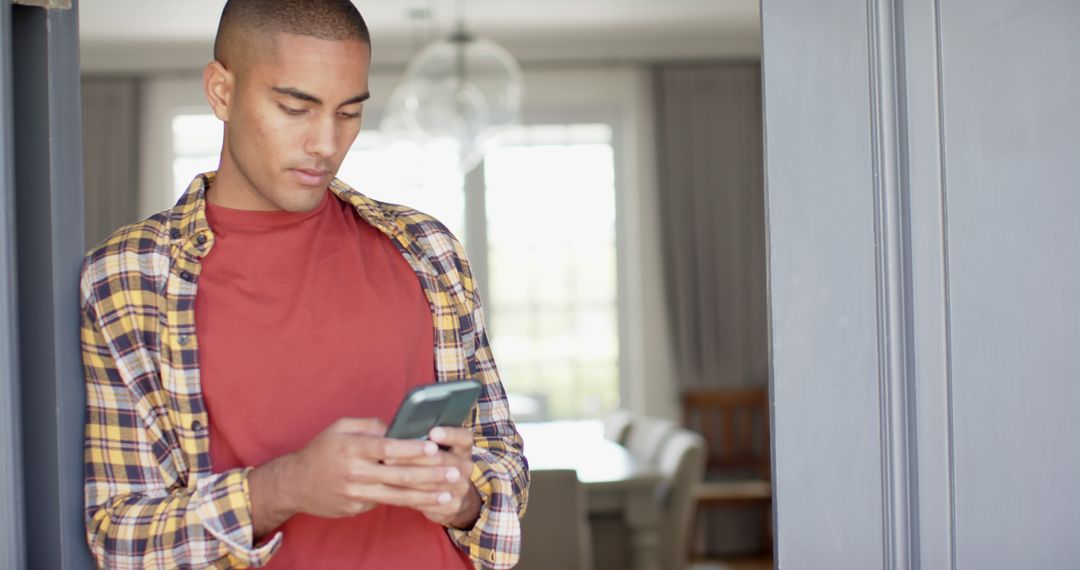 Young man engaged in texting on smartphone in modern home - Free Images, Stock Photos and Pictures on Pikwizard.com