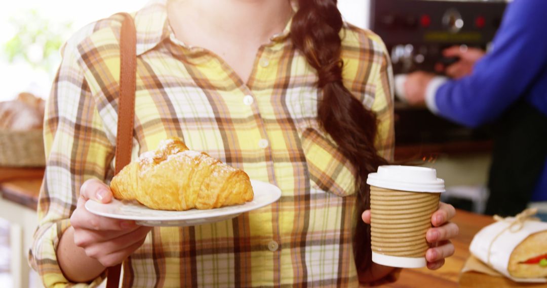 Young Woman Holding Coffee and Croissant in Café - Free Images, Stock Photos and Pictures on Pikwizard.com