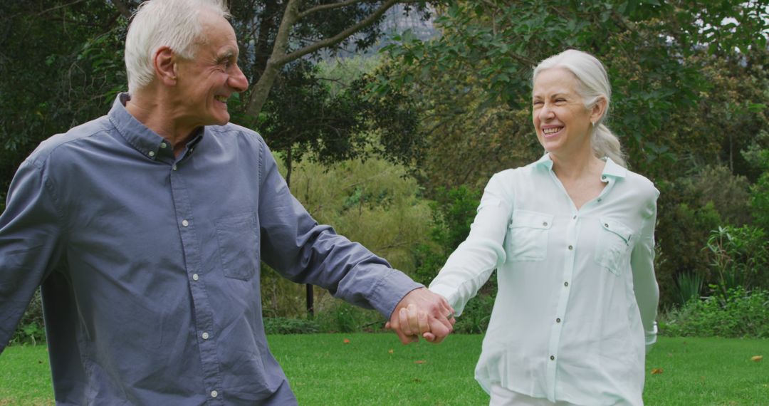 Front view of a happy senior Caucasian man and woman holding hands and walking in a garden - Free Images, Stock Photos and Pictures on Pikwizard.com