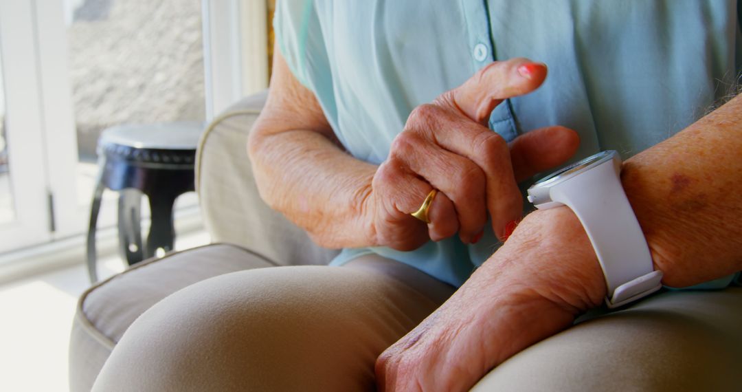 Senior Woman Using Smartwatch While Sitting on Couch at Home - Free Images, Stock Photos and Pictures on Pikwizard.com