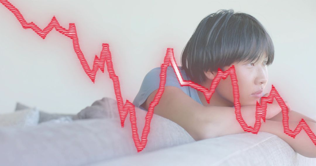 Young man reclining on sofa with red market decline chart overlay
