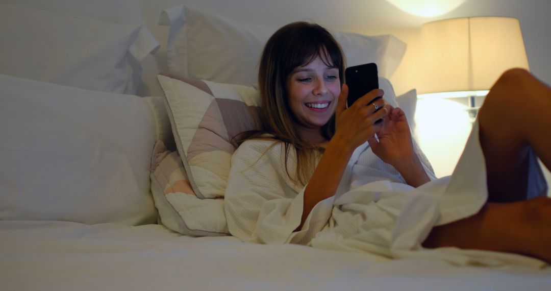 Smiling Woman Relaxing in Bed Using Smartphone at Night - Free Images, Stock Photos and Pictures on Pikwizard.com