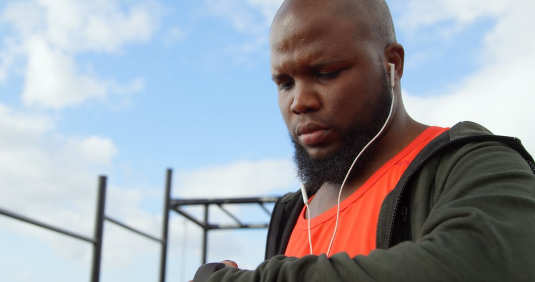 Man Listening to Music While Checking Smartwatch in Park