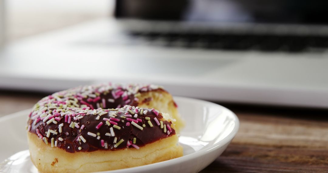 Colorful Sprinkled Donut Near Laptop on Wooden Desk - Free Images, Stock Photos and Pictures on Pikwizard.com