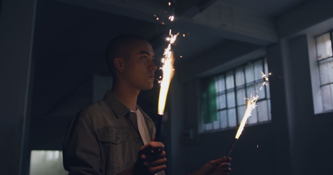 Young Man Holding Sparklers in Industrial Room at Night - Free Images, Stock Photos and Pictures on Pikwizard.com