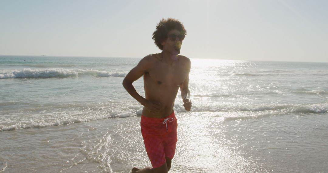 Man Running on Ocean Beach During Sunny Day - Free Images, Stock Photos and Pictures on Pikwizard.com