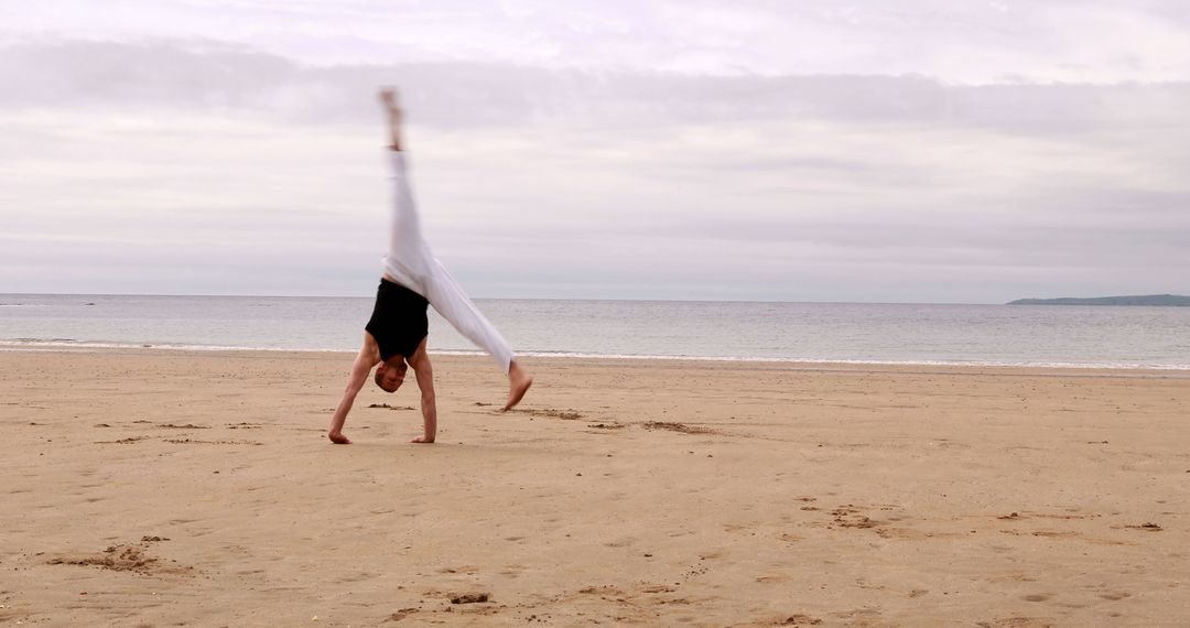 Person Performing Cartwheel on Serene Beach - Free Images, Stock Photos and Pictures on Pikwizard.com