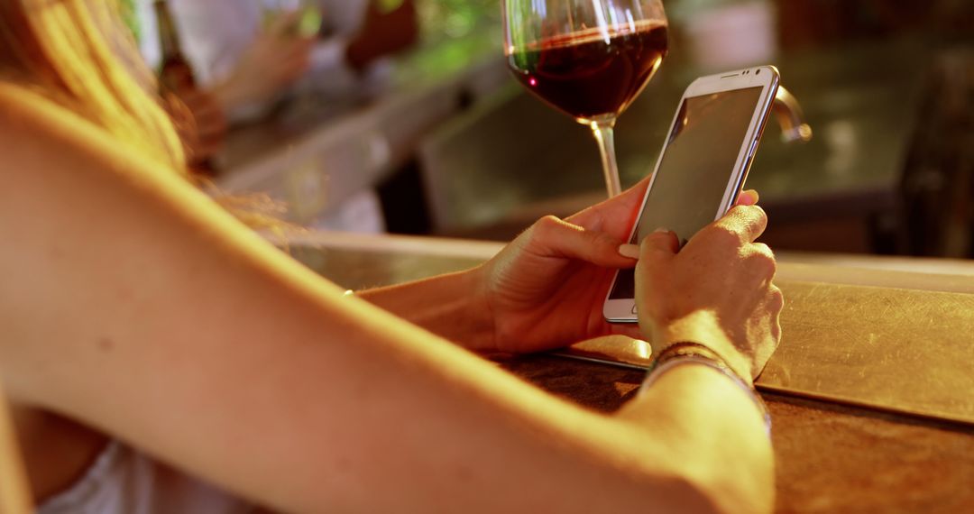 Woman texting on smartphone at bar with glass of wine - Free Images, Stock Photos and Pictures on Pikwizard.com