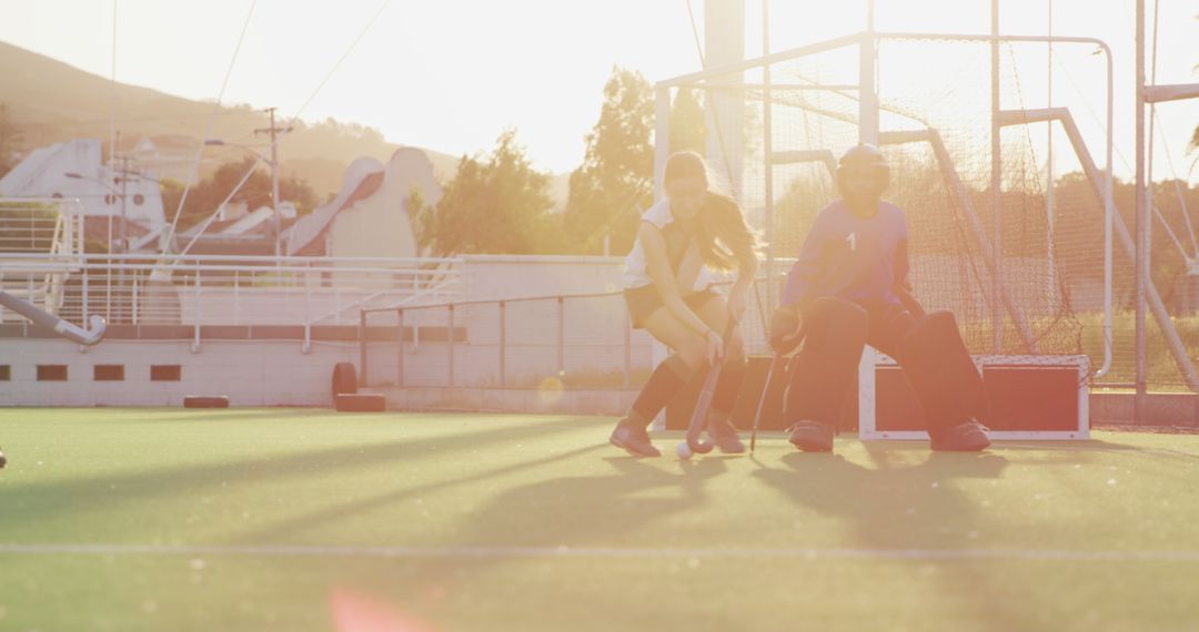 Girls Playing Field Hockey During Sunset on AstroTurf Field - Free Images, Stock Photos and Pictures on Pikwizard.com