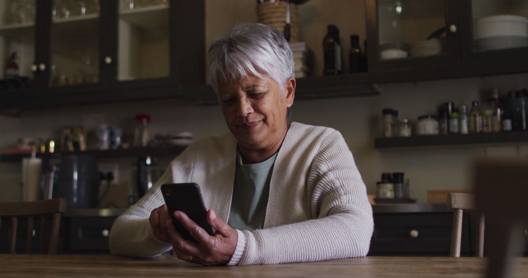 Smiling Senior Woman Using Smartphone in Cozy Kitchen - Free Images, Stock Photos and Pictures on Pikwizard.com