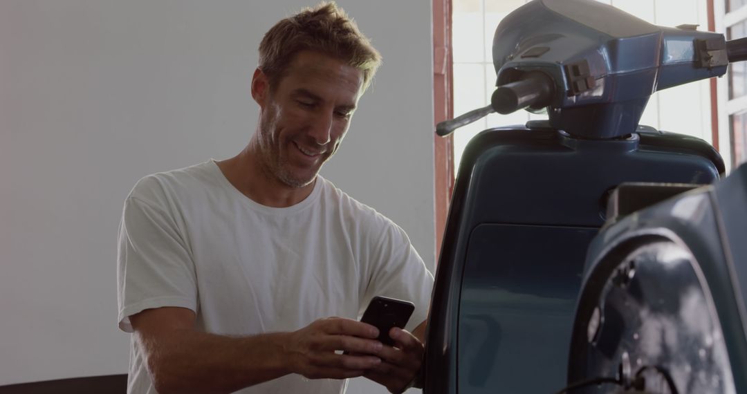 Man Smiling While Using Smartphone Near Vintage Scooter - Free Images, Stock Photos and Pictures on Pikwizard.com