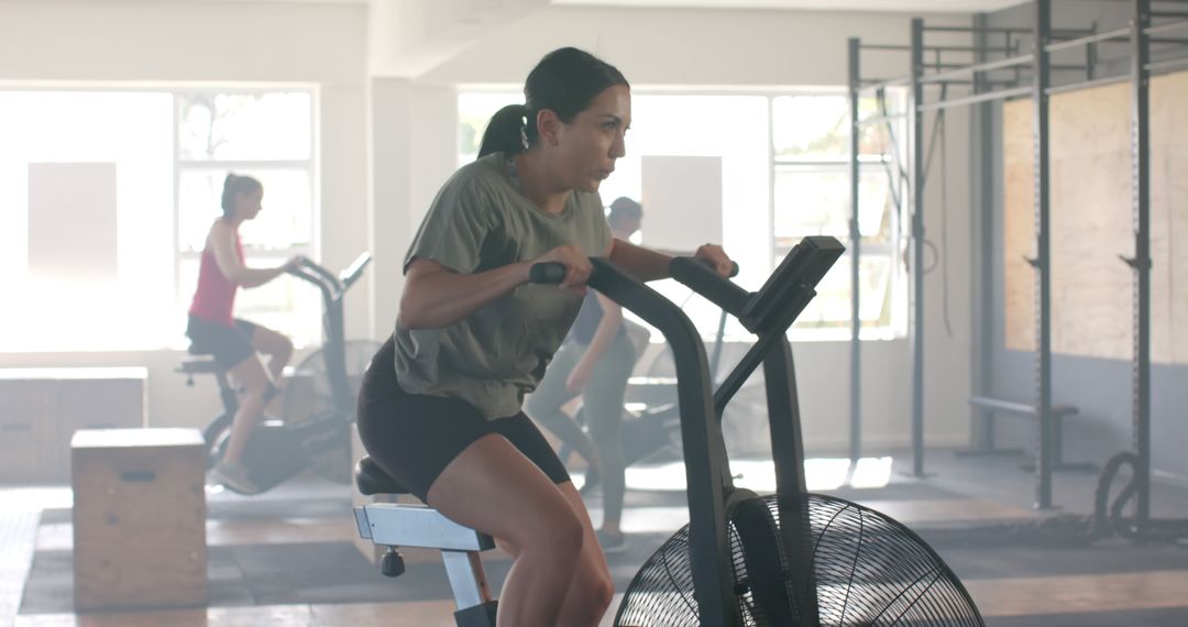 Woman Exercising on Air Bike in Gym - Free Images, Stock Photos and Pictures on Pikwizard.com