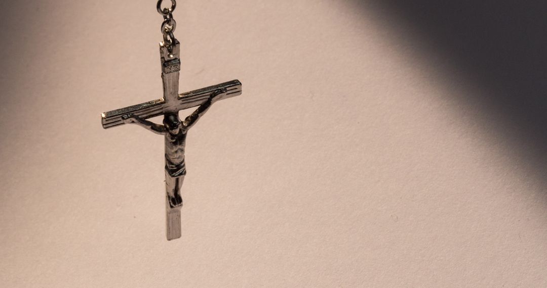 Peaceful Silver Cross Casting Shadow on Light Grey Background