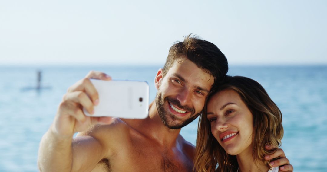 Smiling Couple Taking Selfie on Beach During Sunny Day - Free Images, Stock Photos and Pictures on Pikwizard.com