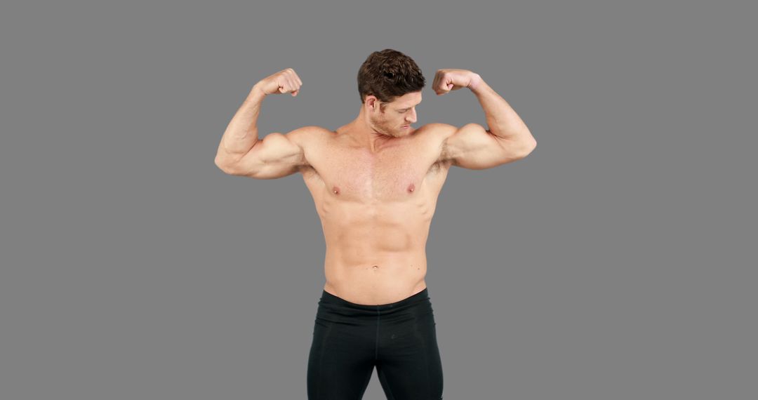 A young Caucasian man is showcasing his muscular physique by flexing his biceps, with copy space - Free Images, Stock Photos and Pictures on Pikwizard.com