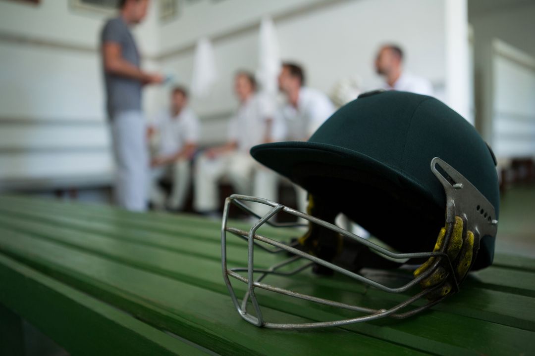 Cricket Helmet on Bench in Locker Room with Team in Background - Free Images, Stock Photos and Pictures on Pikwizard.com