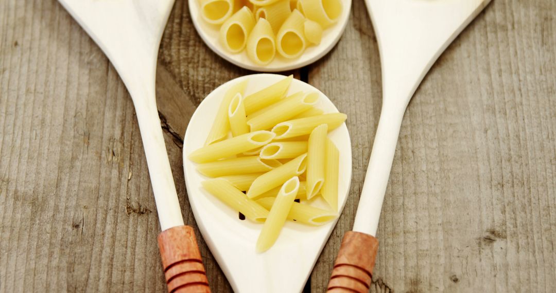 Uncooked Penne Pasta on Wooden Spoons Reflecting Italian Cuisine - Free Images, Stock Photos and Pictures on Pikwizard.com