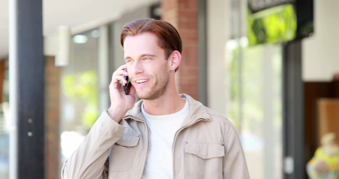 Young man talking on cellphone outdoors with a smile - Free Images, Stock Photos and Pictures on Pikwizard.com