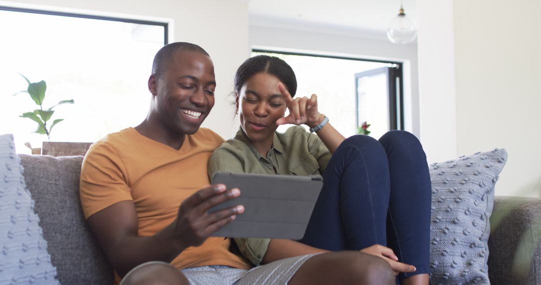 Happy Couple Relaxing on Sofa Watching Tablet Together at Home