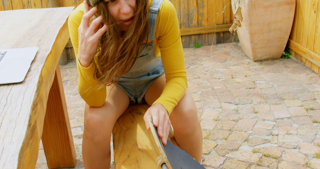 Thoughtful Young Woman in Overalls with Skateboard Outdoors - Free Images, Stock Photos and Pictures on Pikwizard.com