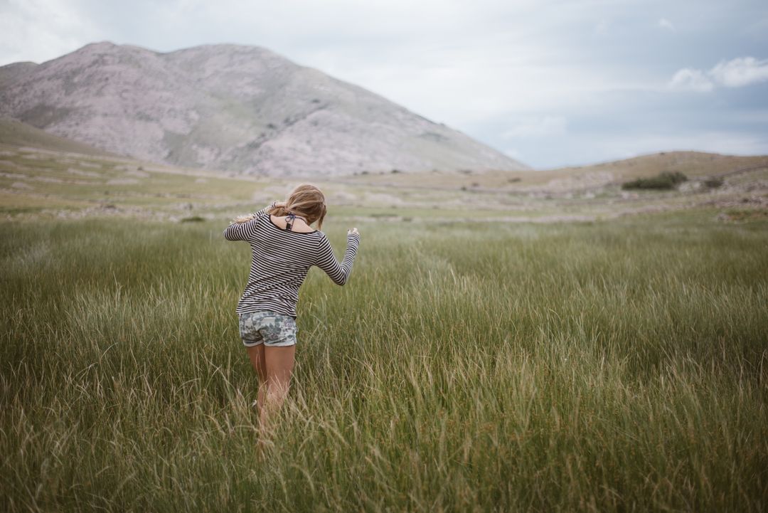 Woman Enjoying Freedom in Expansive Meadow with Mountains