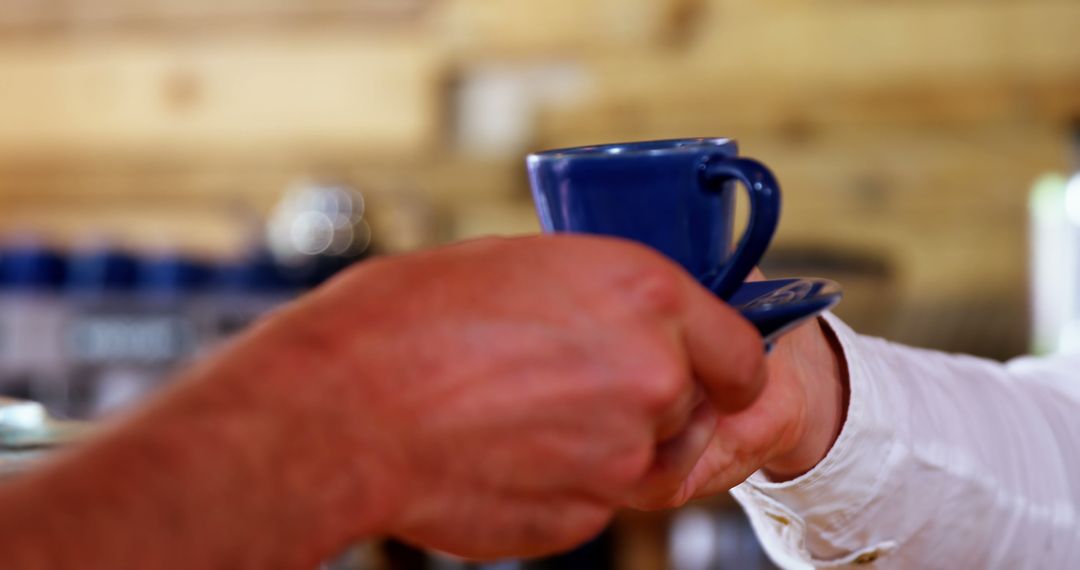 Hands Exchanging Blue Coffee Cup in Cozy Atmosphere - Free Images, Stock Photos and Pictures on Pikwizard.com