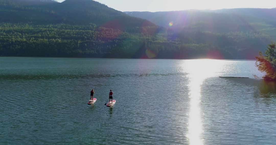 Two People Paddleboarding on Serene Lake at Sunset - Free Images, Stock Photos and Pictures on Pikwizard.com