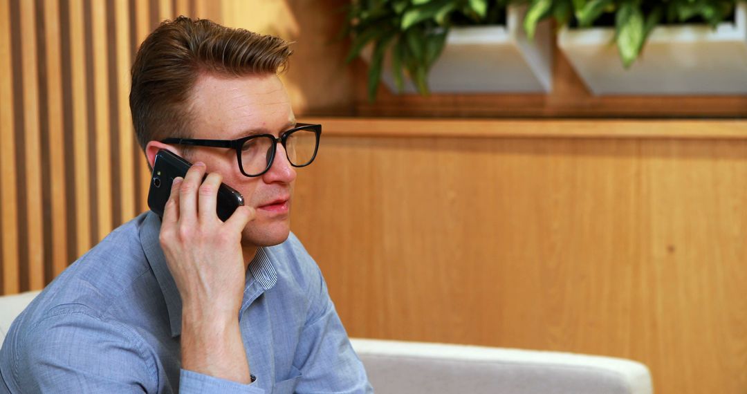 Businessman with Glasses Talking on Phone in Modern Office - Free Images, Stock Photos and Pictures on Pikwizard.com