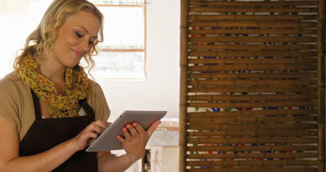 Smiling Female Potter Using Tablet in Studio