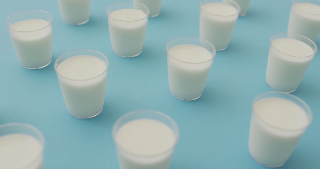 Image of row of glasses of milk on blue background - Free Images, Stock Photos and Pictures on Pikwizard.com