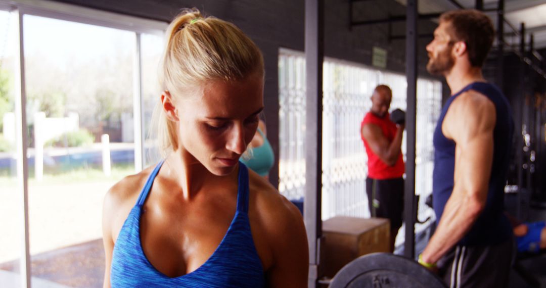 Focused Woman Working Out in Gym with Others in Background - Free Images, Stock Photos and Pictures on Pikwizard.com