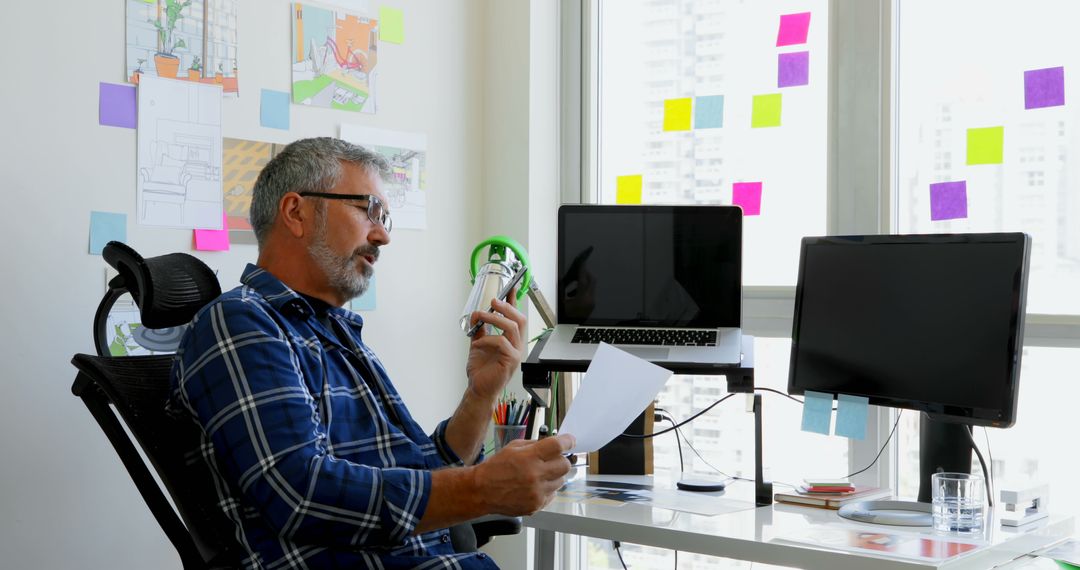 Middle-Aged Man Discussing Document Over Phone in Home Office