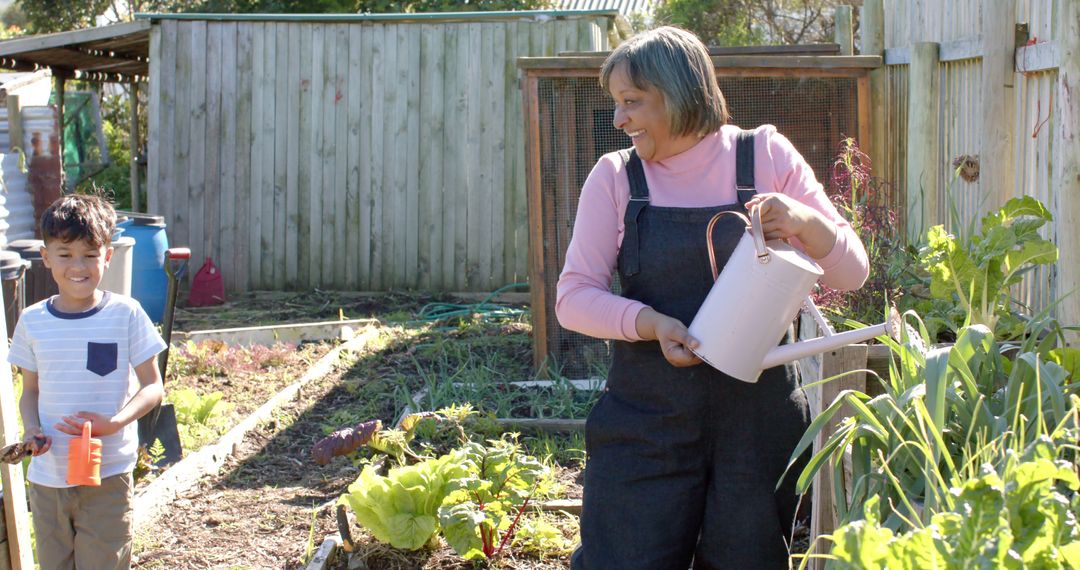 Senior woman watering garden with grandson on sunny day - Free Images, Stock Photos and Pictures on Pikwizard.com