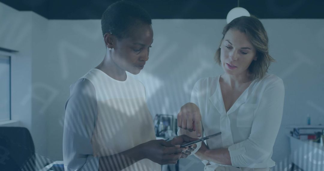 Female Professionals Collaborating on Touchscreen Device in Modern Office